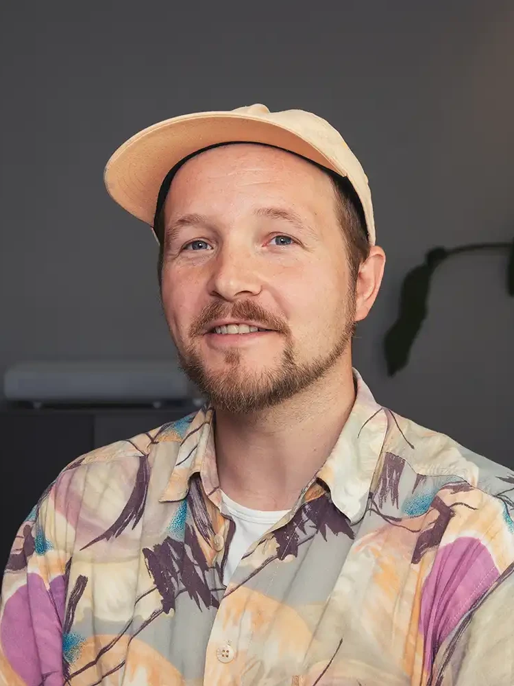 portrait of Daniel the art director. He is wearing a light but colorful shirt and a light cap